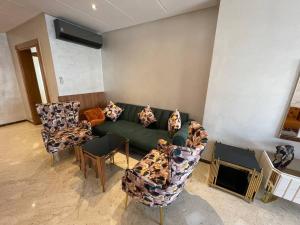 a living room with a green couch and chairs at Appartement de luxe à peninsula in Casablanca