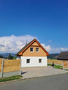 a white and orange house with a wooden fence at Chata Štíty in Štíty