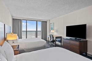 a hotel room with two beds and a flat screen tv at DoubleTree by Hilton Atlantic Beach Oceanfront in Atlantic Beach