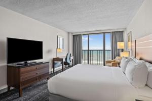DoubleTree by Hilton Atlantic Beach Oceanfront في أتلانتيك بيتش: غرفة فندقية بسرير وتلفزيون بشاشة مسطحة