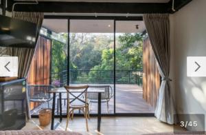 a living room with a table and chairs and a balcony at Maesa Greenery Hill SHA in Mae Rim