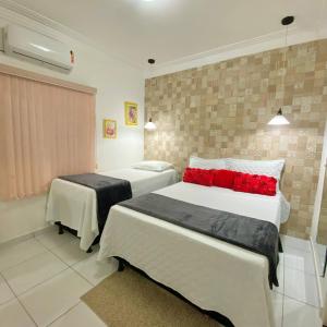ein Hotelzimmer mit 2 Betten und roten Kissen in der Unterkunft Casa de temporada Raio de sol in Piranhas