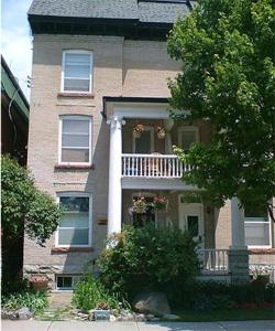 a large brick house with a porch and a balcony at Australis Guest House in Ottawa