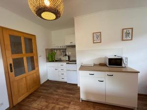 eine Küche mit weißen Schränken und einer Mikrowelle auf der Theke in der Unterkunft Apartment Brusinka in Kašperské Hory