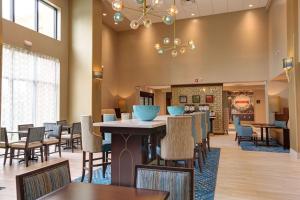 a restaurant with tables and chairs and a fireplace at Hampton Inn & Suites by Hilton Tampa Busch Gardens Area in Tampa