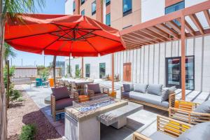 a patio with a red umbrella and couches and a fire pit at Hampton Inn & Suites Phoenix - East Mesa in Gilbert in Gilbert