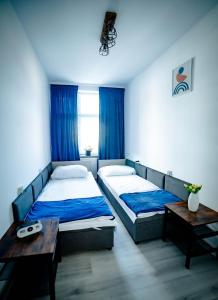 2 camas en un dormitorio con cortinas azules y mesa en LOFT APARTAMENT NAMYSŁÓW, en Namysłów