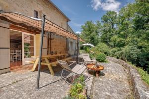 a patio with a table and chairs and a wooden table at Le Moulin de Bafave in Périssac