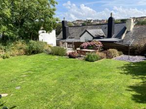 una casa con un cortile verde con una panchina di Devon Cottage in Lovely Georgeham a Georgeham