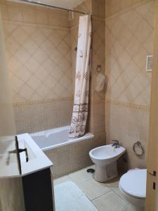 een badkamer met een toilet, een bad en een wastafel bij Beira Mar Apartment in Portimão