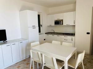 een witte keuken met een witte tafel en stoelen bij Marasusa Apartments Tramontana in Parghelia