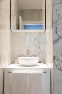 bagno bianco con lavandino e specchio di Brera Apartments in San Babila a Milano