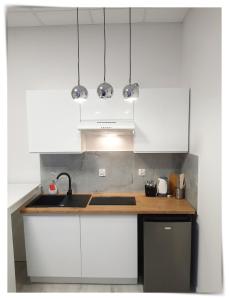 een keuken met witte kasten en een spoelbak bij SouvenirAppart Sienkiewicza in Bydgoszcz