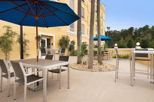 un patio con mesa, sillas y sombrillas azules en Hampton Inn & Suites Lake City, en Lake City