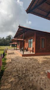 una casa de ladrillo con un pabellón junto a un campo en 5 Mile Beach Resort en Kumta