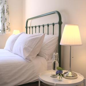 Meadowbrook House في Halwell: سرير بمخدات بيضاء ومصباح على طاولة
