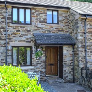 uma casa de tijolos com uma porta de madeira e janelas em Meadowbrook House em Halwell