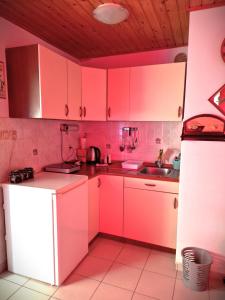 uma cozinha com armários cor-de-rosa e um frigorífico branco em TURIZEM GRABRIJAN, Jasmina Grabrijan s.p. em Adlešiči