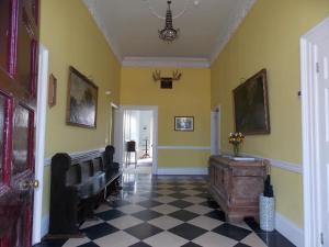 a hallway with yellow walls and a black and white tile floor at Ash Hill B & B in Kilmallock