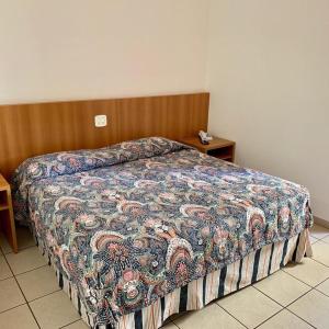um quarto com uma cama com uma colcha colorida em Hotel Flat Alameda em Araçatuba