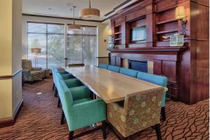 une salle de conférence avec une table en bois et des chaises bleues dans l'établissement Hilton Garden Inn Albuquerque Uptown, à Albuquerque