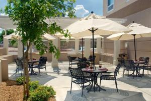 eine Terrasse mit Tischen, Stühlen und Sonnenschirmen in der Unterkunft Hilton Garden Inn Albuquerque Uptown in Albuquerque