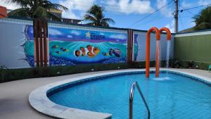 een zwembad voor een muur met een muurschildering bij Hotel Enseada dos Corais in Cabo de Santo Agostinho