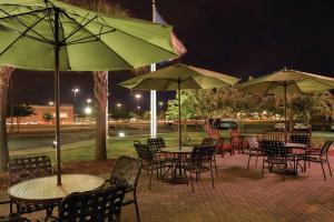 a group of tables and chairs with umbrellas at night at Hilton Garden Inn Warner Robins in Warner Robins