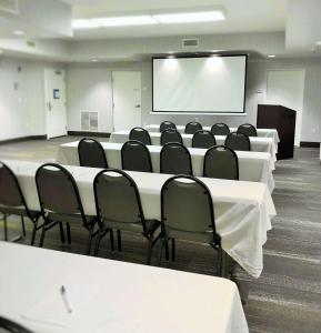 una sala conferenze con tavoli e sedie bianchi e schermo di Hampton Inn Williamsport a Williamsport