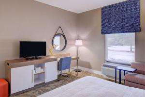 1 dormitorio con escritorio, TV y espejo en Hampton Inn Baton Rouge - Denham Springs, en Denham Springs