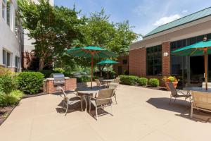 un patio con mesas, sillas y sombrillas en Homewood Suites by Hilton Falls Church en Merrifield