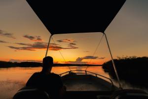 a person on a boat in the water at sunset at ASKIESBOS - Samochima Bush Camp in Shakawe