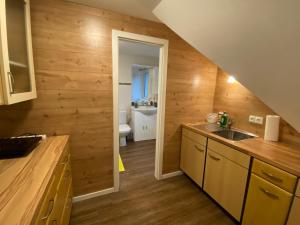 a kitchen with wooden walls and a sink and a bathroom at 1Zi Ferienwohnung bis zu 3 Personen für Dienstreisende in Loßburg Schwarzwald in Loßburg