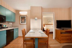 eine Küche mit einem Tisch und ein Zimmer mit einem Bett in der Unterkunft Homewood Suites by Hilton Falls Church in Merrifield