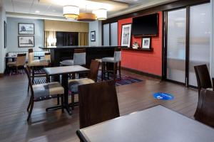 una sala d'attesa con tavoli, sedie e TV di Hampton Inn Columbia a Columbia