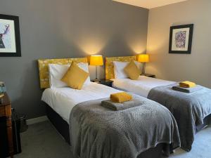 2 camas en una habitación de hotel con almohadas amarillas en Ardenbeg, en Grantown-on-Spey