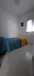 Cama en habitación blanca con manta azul y amarilla en LA CASITA SERRANA, en Puerto de Béjar