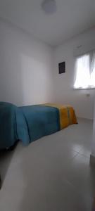 un letto in una camera bianca con una coperta blu e gialla di LA CASITA SERRANA a Puerto de Béjar