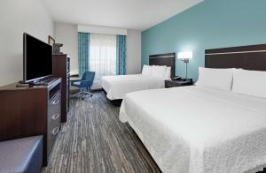 a hotel room with two beds and a flat screen tv at Hampton Inn & Suites Childress in Childress