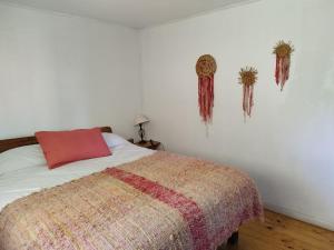 1 dormitorio con cama con almohada roja y adornos en la pared en Cabañas Zarapito, en Quellón