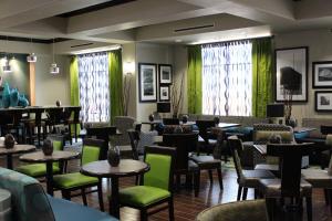 un restaurant avec des tables, des chaises et des rideaux verts dans l'établissement Hampton Inn Cotulla, à Cotulla
