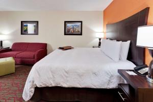 een hotelkamer met een groot bed en een rode stoel bij Hampton Inn Seneca Falls in Seneca Falls