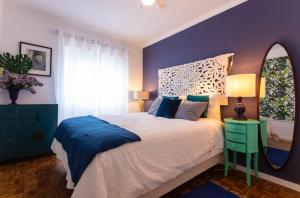 エリセイラにあるSea Ceiling - Ericeiraの紫の壁のベッドルーム1室、鏡付きのベッド1台が備わります。