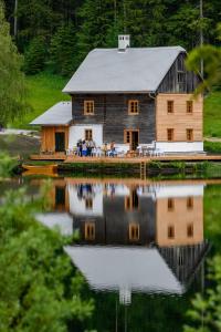 a barn reflecting in the water with people sitting on the dock at Seehaus Walster10 in Mariazell