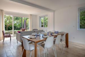 a dining room with a table and chairs and a couch at Maison moderne avec jardin pour 8 à La Baule in La Baule +29 photos