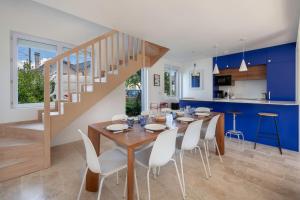 a dining room and kitchen with a wooden table and white chairs at Maison moderne avec jardin pour 8 à La Baule in La Baule