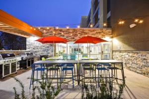 un patio con mesas, sillas y sombrillas rojas en Home2 Suites By Hilton Maumee Toledo en Maumee