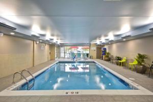 a pool in the middle of a building with chairs and tables at Home2 Suites By Hilton Maumee Toledo in Maumee