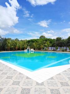 een groot blauw zwembad met palmbomen op de achtergrond bij L J in Trinidad