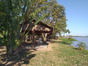 een hut met een tafel en een stoel naast het water bij L J in Trinidad
